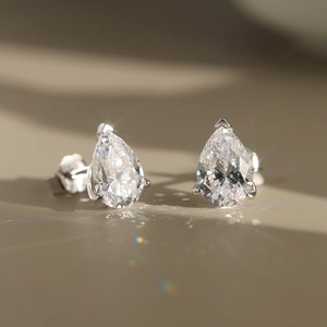 Macro shot of pear-cut zircon earrings with silver three-prong setting and rainbow light refraction