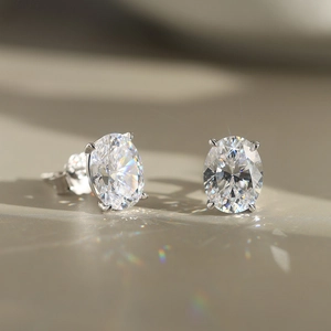 Macro shot of oval cut zircon earrings with four-prong silver setting and rainbow light refraction