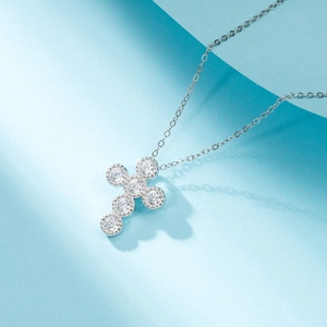 Collier croix en argent poli orné de zircons ronds brillants sur un fond bleu minimaliste