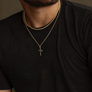 Dettaglio della collana da uomo con ciondolo a croce dorata e catena cubana a strati