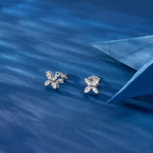 Macro detail of sparkling diamond-set windmill earrings on wavy blue background