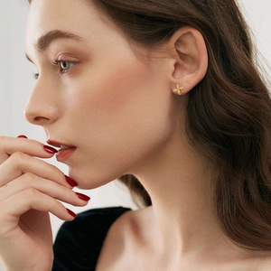 Elegant gold windmill stud earrings with sparkling crystals worn by a female model