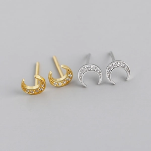 Détail macro de boucles d'oreilles croissant de lune en or et argent avec zircones
