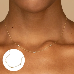 Gros plan d'un collier en argent s925 doré avec trois accents à triple diamant sur modèle
