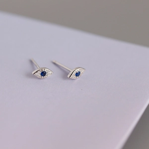 Macro shot of S925 silver evil eye stud earrings with blue center stone and crystals