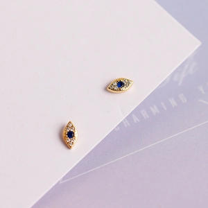 Macro detail of gold evil eye stud earrings with blue sapphire and pavé diamonds
