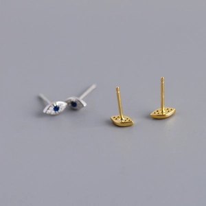Detail view of Evil Eye stud earrings in silver diamond-set and gold hollow-out finishes
