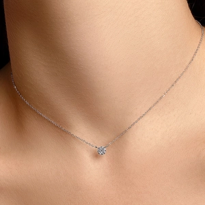 Gros plan d'un collier délicat en argent avec pendentif rond en zircon brillant sur modèle