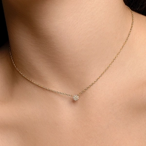 Détail d'un collier chaîne dorée délicate avec un pendentif rond scintillant en micro-pave