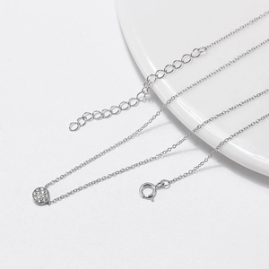 Collier élégant à pendentif rond en argent serti de zircones sur une assiette blanche