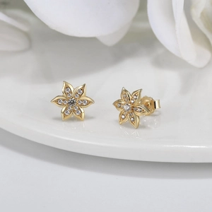 Elegant gold flower stud earrings with sparkling zircon petals on white ceramic plate