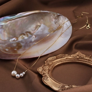 Elegant gold chain necklace featuring four graduated natural freshwater pearls on silk fabric