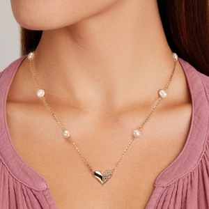 Detail of 925 silver necklace with baroque pearls and heart pendant on a female model