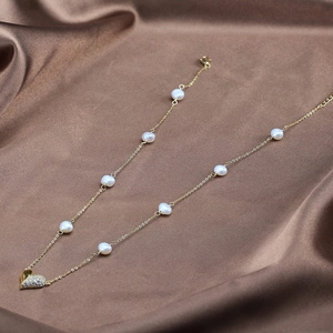 Macro detail of 925 silver gold heart pendant with baroque pearls on brown satin