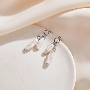Gros plan détaillé de boucles d'oreilles en perles baroques sur un plateau blanc