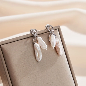 Détail de boucles d'oreilles en perles baroques sur un coffret à bijoux doré