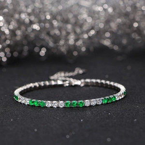 Detail of a 3mm tennis bracelet featuring green and white cubic zirconia in claw settings