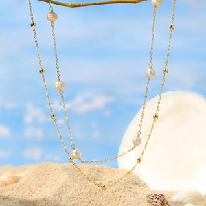925 sterling silver gold necklace with white pearls on a beach with shells and sand