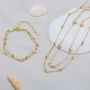 925 silver gold-plated pearl necklace and bracelet set shown on sea shells background
