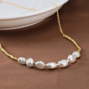 Baroque freshwater pearl necklace with gold-plated tubes on brown textured fabric