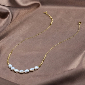 Detail of seven baroque pearls on a gold chain over luxurious brown silk fabric