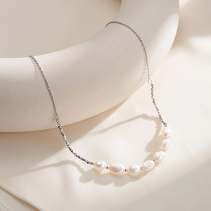 Detailed view of S925 silver necklace featuring baroque pearls on ceramic stand