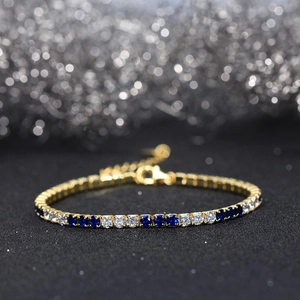 Macro detail of 3MM tennis bracelet featuring blue and clear cubic zirconia in gold setting