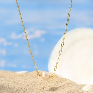Gros plan du collier en argent S925 doré avec pendentif perle d'eau douce sur plage