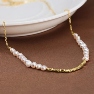 Macro detail of Baroque freshwater pearls and 14K gold plated silver tube on the necklace