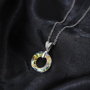Macro view of colorful crystal pendant with diamond accents on black silk background