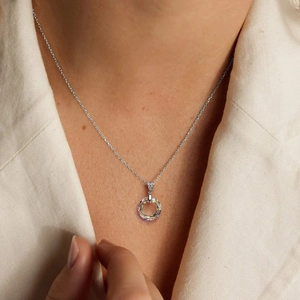 Elegant silver necklace featuring a faceted AB crystal pendant on a beige blazer background