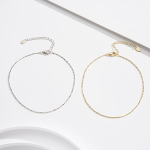 Dettaglio di catene minimaliste in oro e argento con chiusura a moschettone e tag estensibili