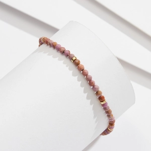 Detailed shot of faceted natural stone beads with gold spacers on a jewelry display stand
