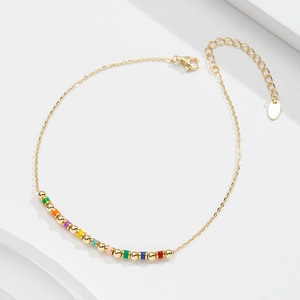 Macro detail of S925 sterling silver anklet with rainbow enamel beads and golden spheres