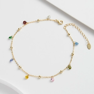 Détail d'une chaîne de cheville dorée ornée de zircons multicolores et d'un fermoir mousqueton