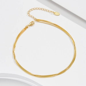 Close-up of triple-layered gold snake chain anklet with lobster clasp and extender