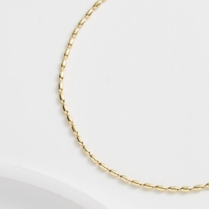 Detaillierte Makroansicht der minimalistischen goldene Olivenperlenkette mit polierter Oberfläche