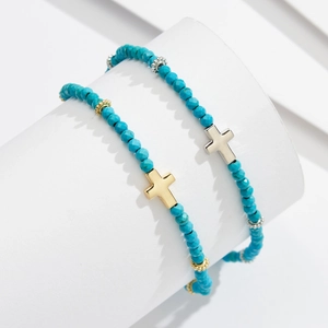 Turquoise beaded anklet set with silver and gold cross charms on a white display
