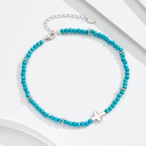 Turquoise bead necklace with S925 silver cross pendant on a white geometric display