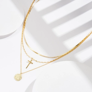 Detailed view of 3-layer gold plated snake chain necklace with cross and coin pendants
