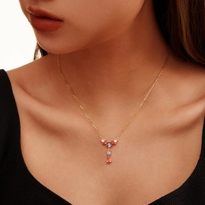 Detail of elegant gold tassel necklace with purple and pink zircon stones on model