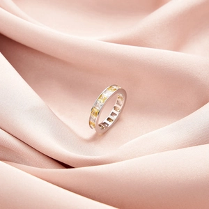 Bague en argent avec zircons carrés jaunes et blancs sur un tissu en soie rose