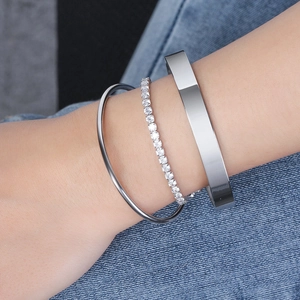 Gros plan d'un ensemble de trois bracelets argentés avec zircons sur denim bleu