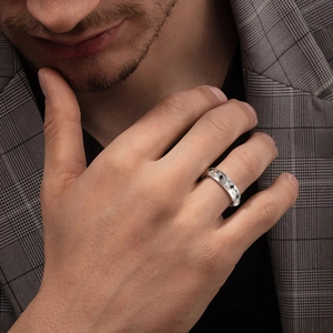 Close-up of a men's silver geometric ring with black gemstones on a suit background