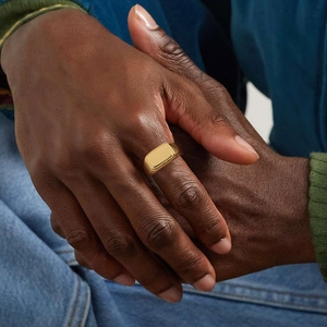 Close-up of a polished gold signet ring for men featuring a minimalist rectangular face