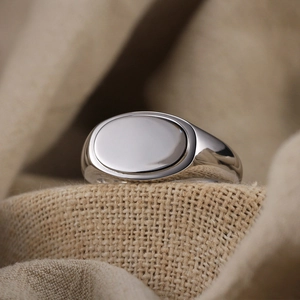Close-up of polished S925 sterling silver signet ring on textured beige fabric