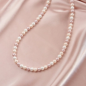 Detailed curve layout of white and pink pearls on soft satin fabric for stylish necklaces