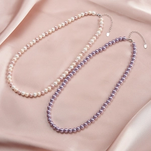 Detail of purple and pink pearl necklaces with silver clasp on pink silk background
