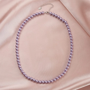 Detail of purple pearl necklace with silver lobster clasp on a soft pink silk background