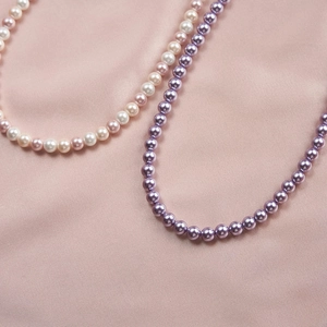 Close-up of pastel and purple pearl necklaces on soft pink satin fabric